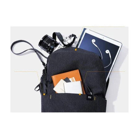 Kadr serii Mi Casual Daypack (wariant ciemny): otwarta komora główna z tabletem, aparatem i notesem