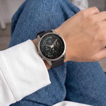 Garmin Fenix z czarnym paskiem Silicone na nadgarstku kobiety siedzącej w dżinsach