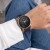Garmin Fenix z czarnym paskiem Silicone na nadgarstku kobiety siedzącej w dżinsach