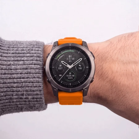 Garmin Fenix z pomarańczowym paskiem Silicone na nadgarstku mężczyzny w swetrze