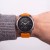 Garmin Fenix z pomarańczowym paskiem Silicone na nadgarstku mężczyzny w swetrze