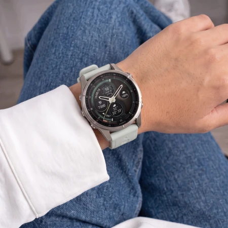 Garmin Fenix z szarym paskiem Silicone na nadgarstku kobiety siedzącej w dżinsach