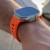 Pomarańczowy pasek Iconband Line na nadgarstku mężczyzny – Apple Watch Ultra z niebieską tarczą
