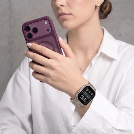 Kobieta w białej koszuli z fioletowym telefonem – Apple Watch Ultra z bransoletą Starlight na nadgarstku