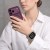 Kobieta w białej koszuli z fioletowym telefonem – Apple Watch Ultra z bransoletą Starlight na nadgarstku