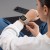 Kobieta w białej koszuli i dżinsach patrzy na Apple Watch Ultra z bransoletą Starlight