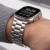 Srebrna bransoleta Stainless z Apple Watch Ultra na nadgarstku mężczyzny w szarym swetrze