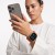Kobieta trzyma telefon przy twarzy – Apple Watch z pomarańczowym paskiem Nylon Sport na nadgarstku