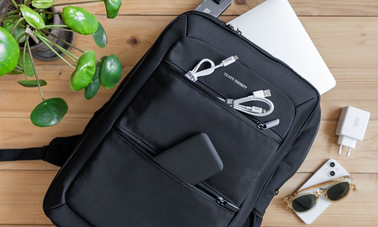Przednie kieszenie plecaka Silver Monkey Modern z kablami i powerbankiem, obok laptop i ładowarka — zdjęcie producenta