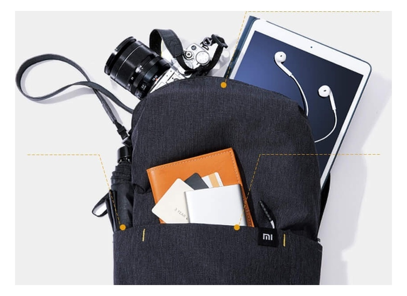 Kadr serii Mi Casual Daypack (wariant ciemny): otwarta komora główna z tabletem, aparatem i notesem