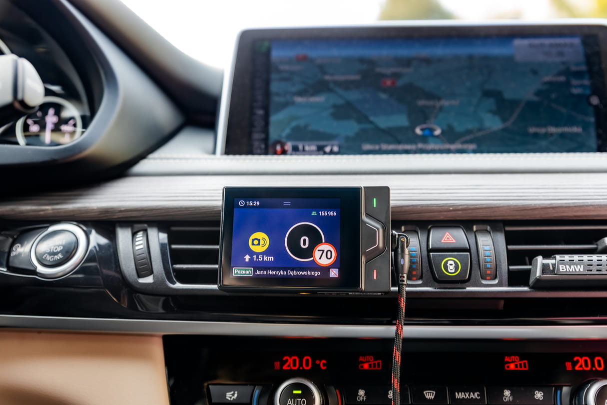 Yanosik RS poziomo w BMW przy nawiewach, podłączony kablem; ekran 0, limit 70 i ikona ostrzeżenia