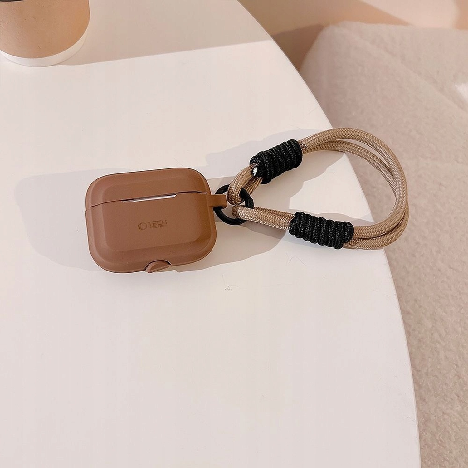 Etui Silicone Rope czekoladowe ze smyczą na stoliku obok fotela