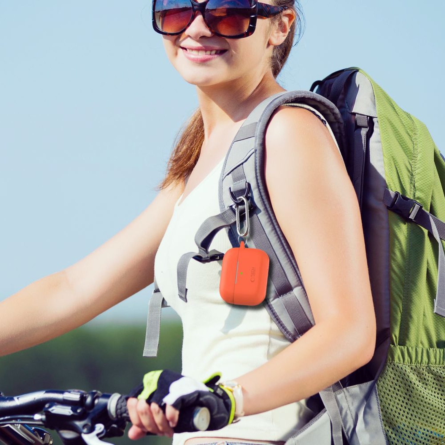 Pomarańczowe etui Silicone Hook przypięte do paska plecaka rowerzystki