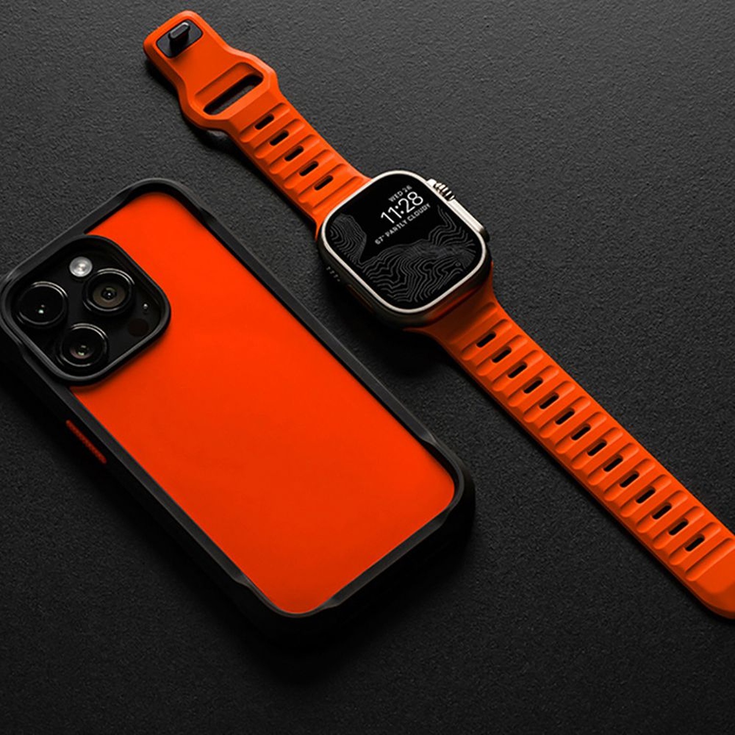 Pomarańczowy pasek Iconband Line na zegarku obok pomarańczowego etui na telefon – zdjęcie producenta