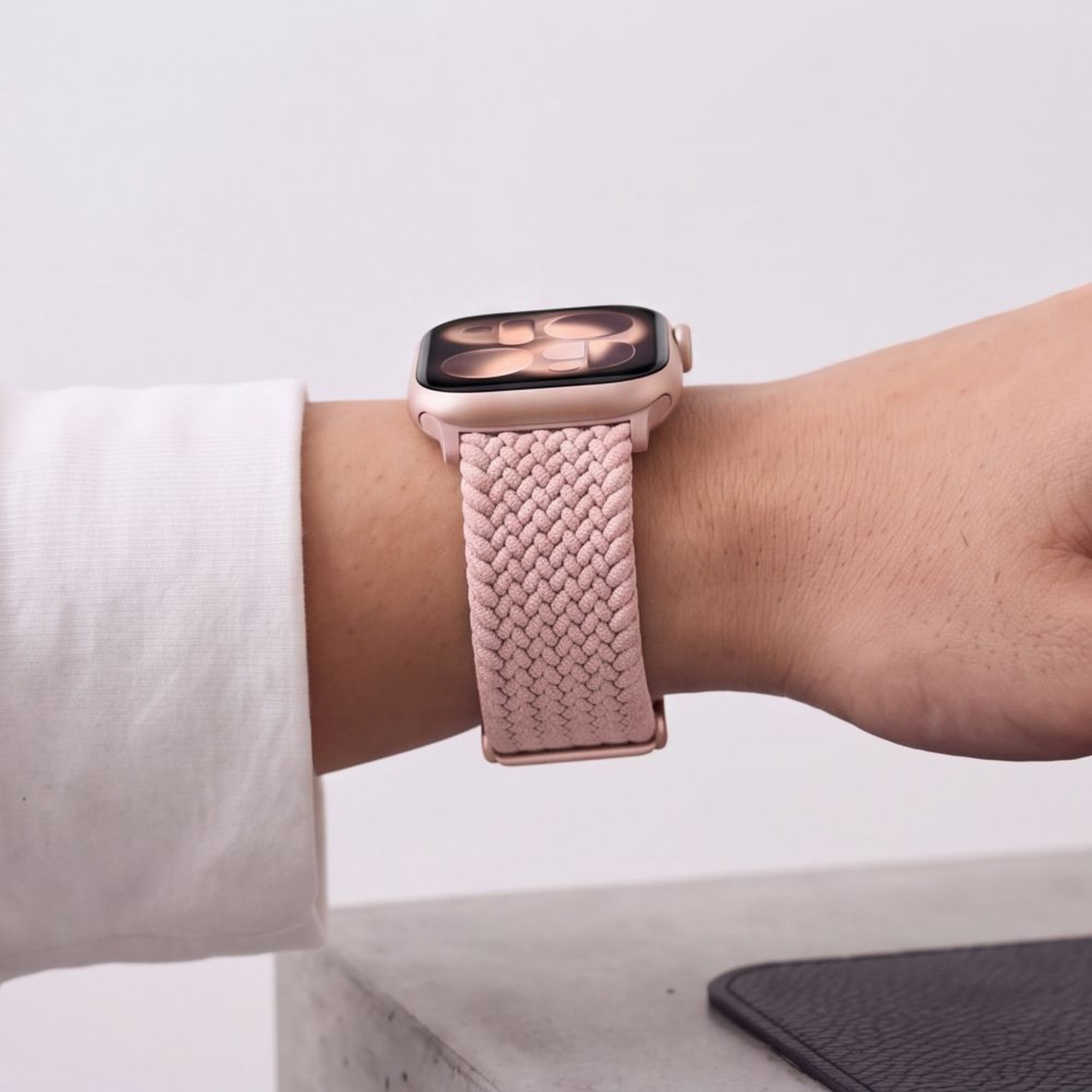 Apple Watch z różowym (Dusty Rose) paskiem NylonMag na nadgarstku kobiety w białej koszuli